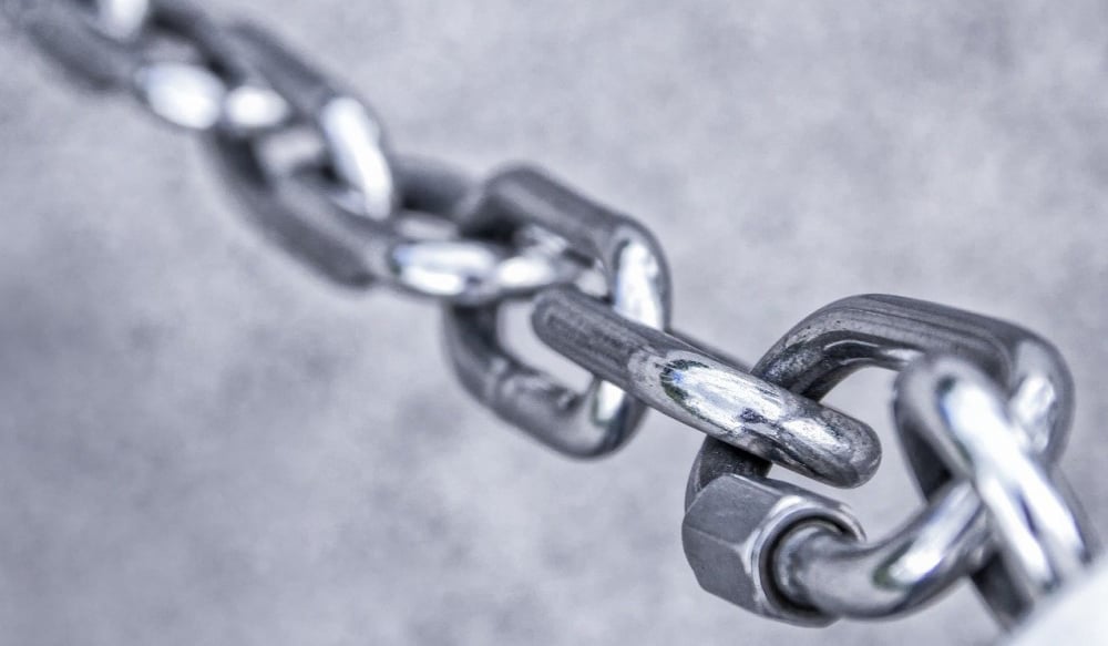 3 grey metal chain links on grey background