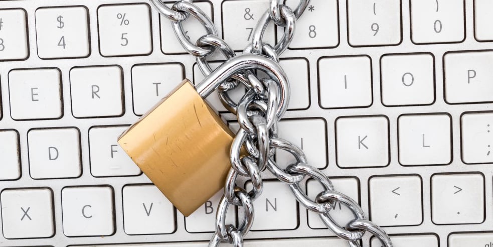 Chains and closed padlock on white keyboard