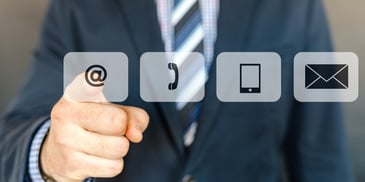 Man in suit and tie pointing at email, phone and tablet icons