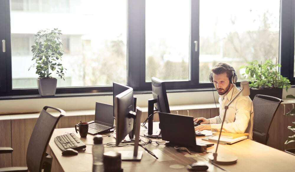 Man with headphones and in white shirt working on the laptop