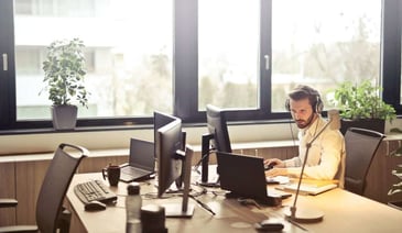 Man with headphones and in white shirt working on the laptop