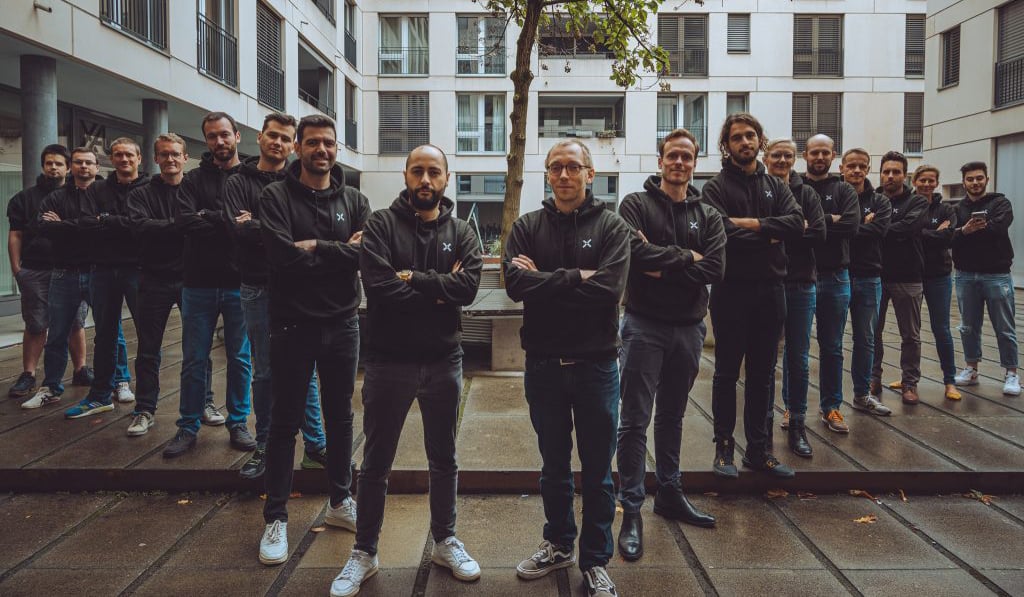 People in dark hoodies standing with their arms crossed 