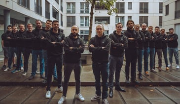 People in dark hoodies standing with their arms crossed 